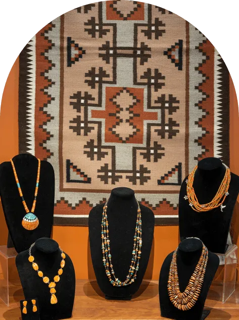 A display of jewelry against a textile hanging on the wall.