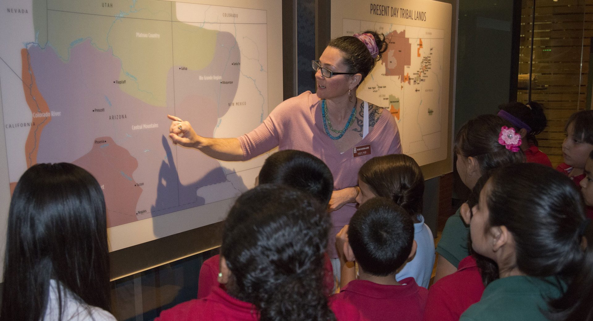 A woman pointing to a map in front of a group of children.