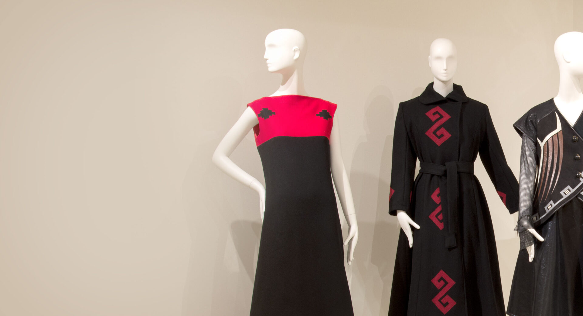 Three mannequins wearing black and red dresses.
