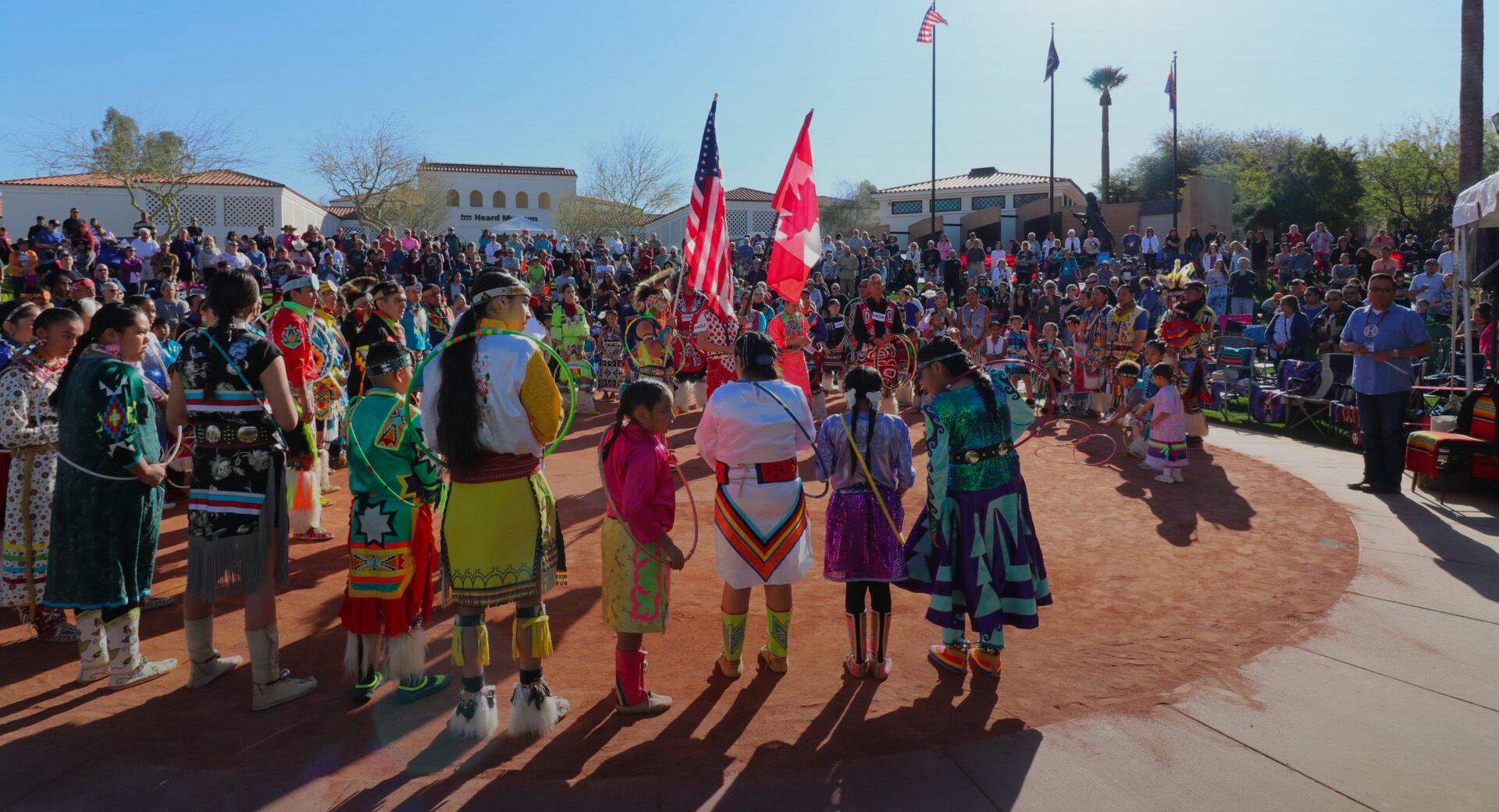 A group of Native American people with hoops standing in a circle outside of the Heard Museum.
