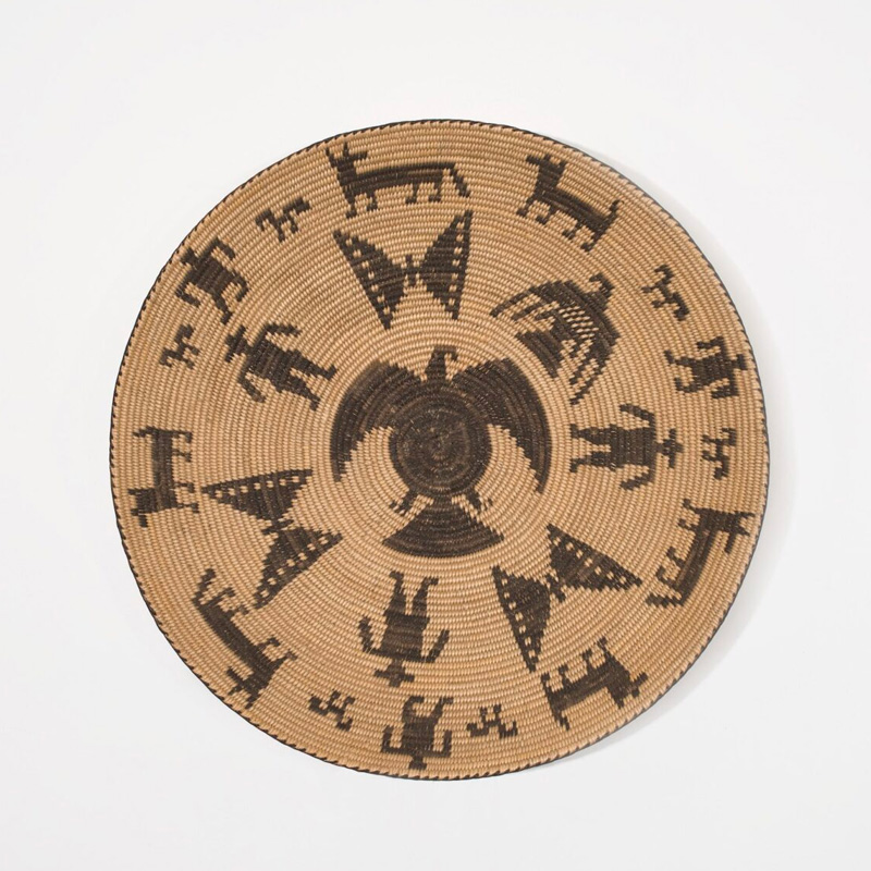 A woven basket with a black and brown design on it that depict different animals.