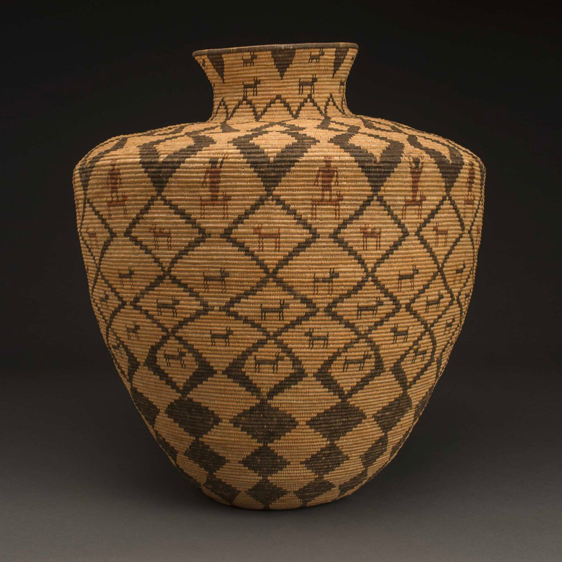A woven vase with geometric designs on it.