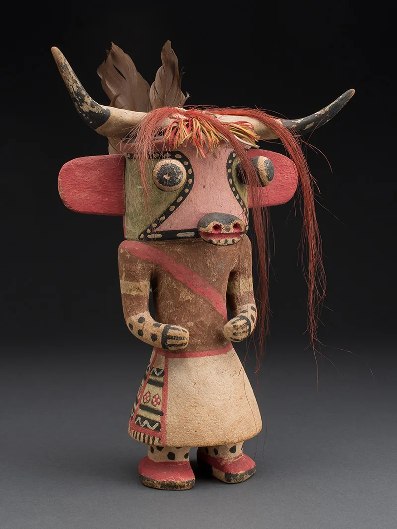 A sculpture of a cow with feathers and horns.