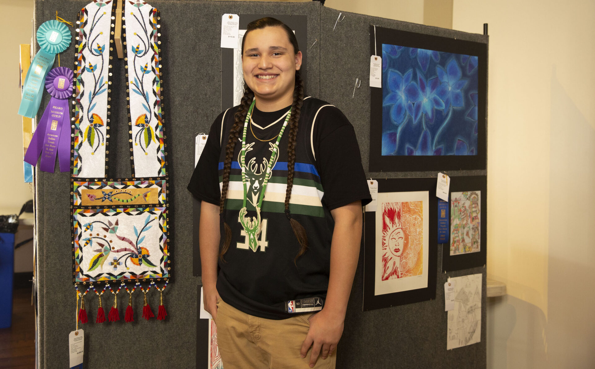 A young man standing in front of a display of art.