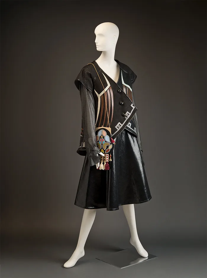 A mannequin wearing a black leather dress and handbag.