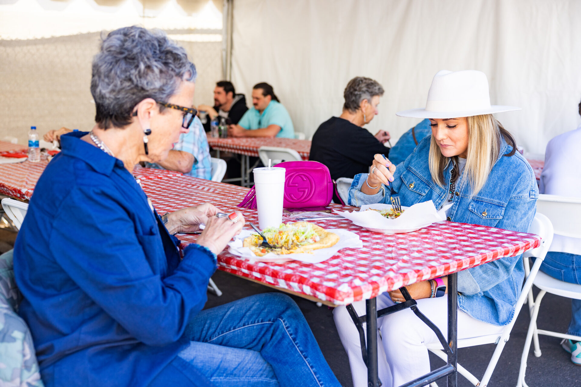 Two women eating at a table in a tent.