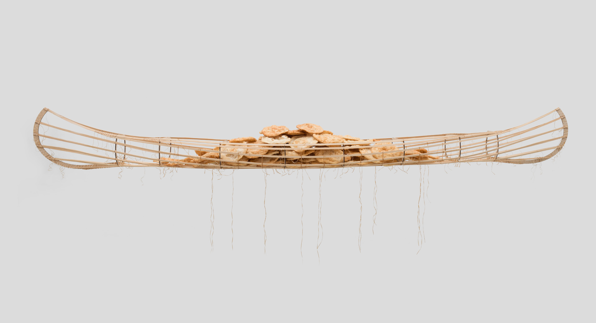 Framework of a wooden canoe filled with rocks.