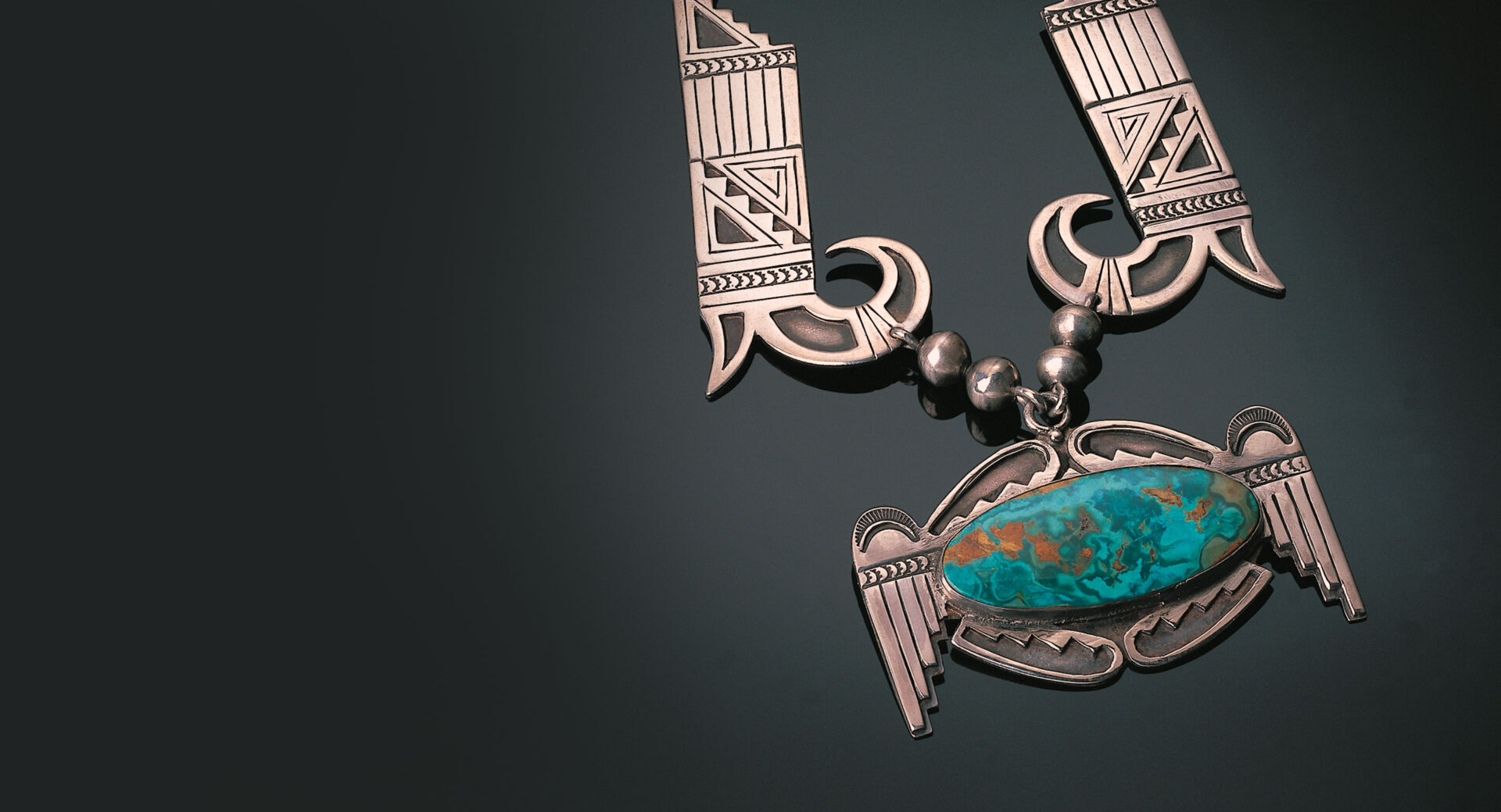 A bronze necklace with a turquoise stone on it.