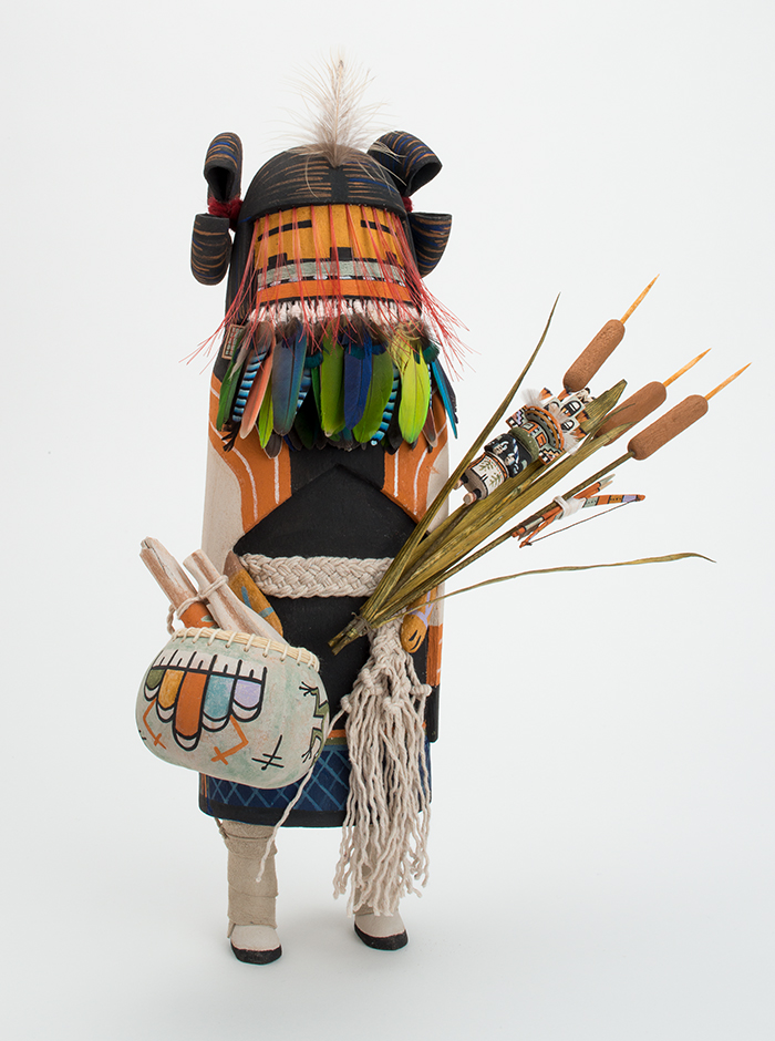 A sculpture with feathers holding a bag and cattails.