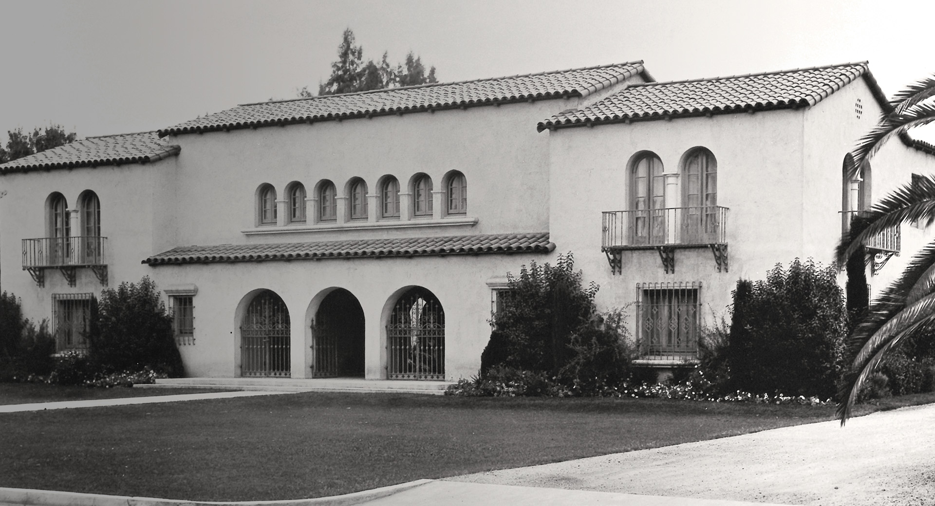 A black and white photo of a building with palm trees.