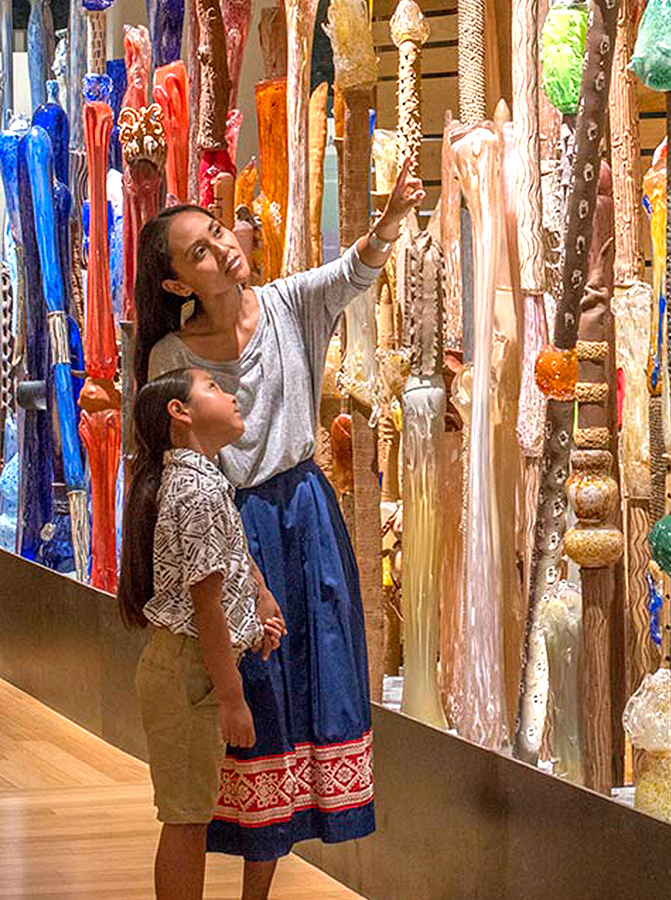 A woman and a child looking at a display of colorful sticks and glass.