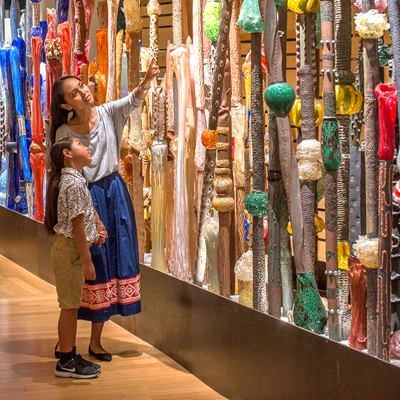 A woman and a child looking at a display of colorful sticks known as Art Fence.