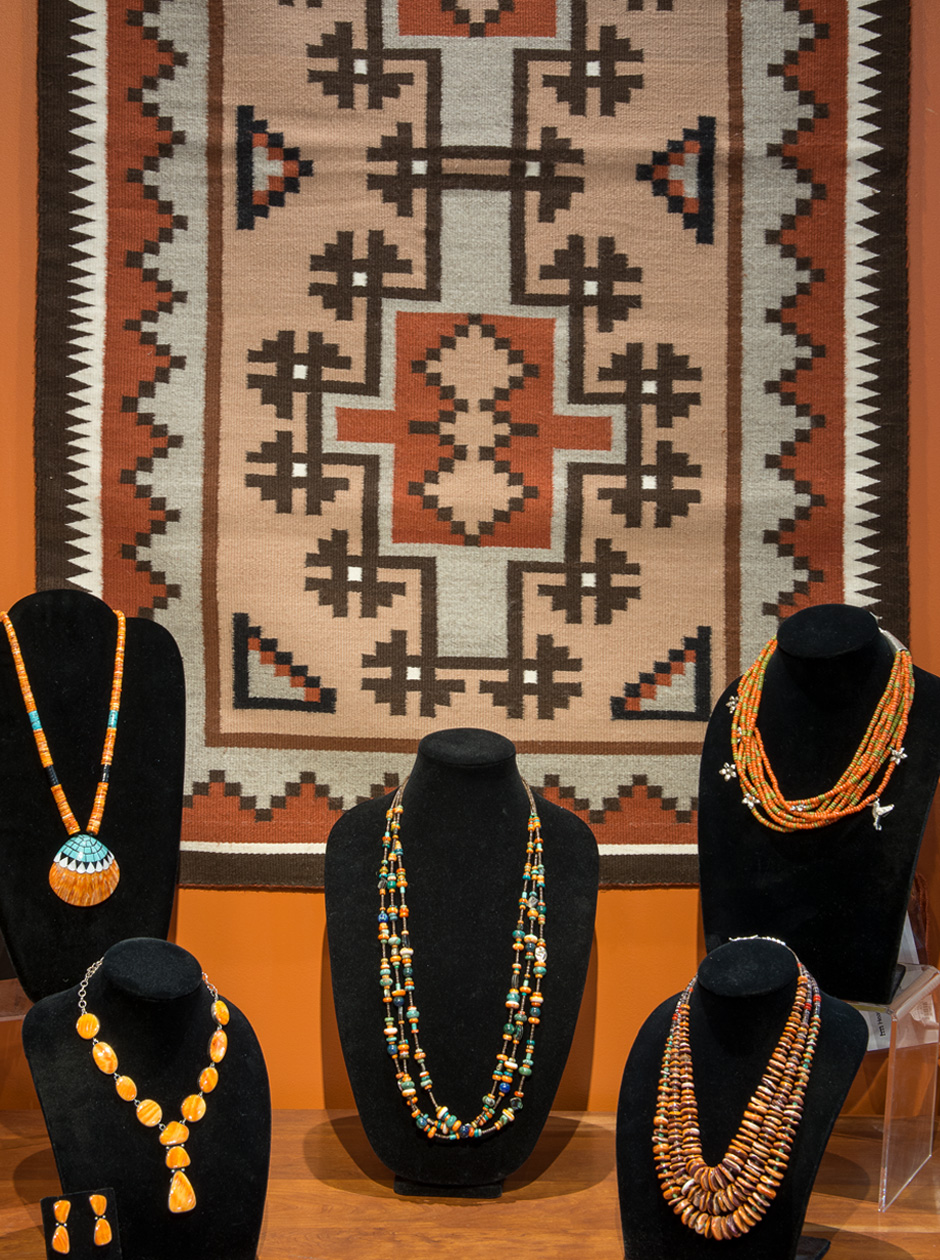 A display of jewelry against a textile hanging on the wall.