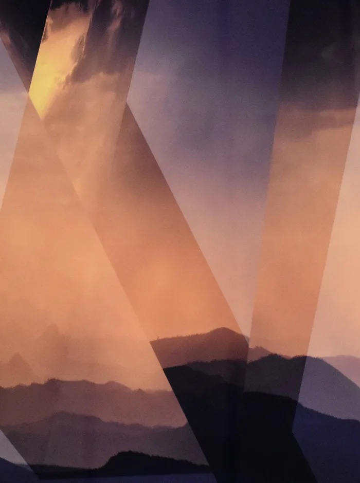 A 3d image still of a geometric shape with orange and yellow cloudy skies and mountains in the background.