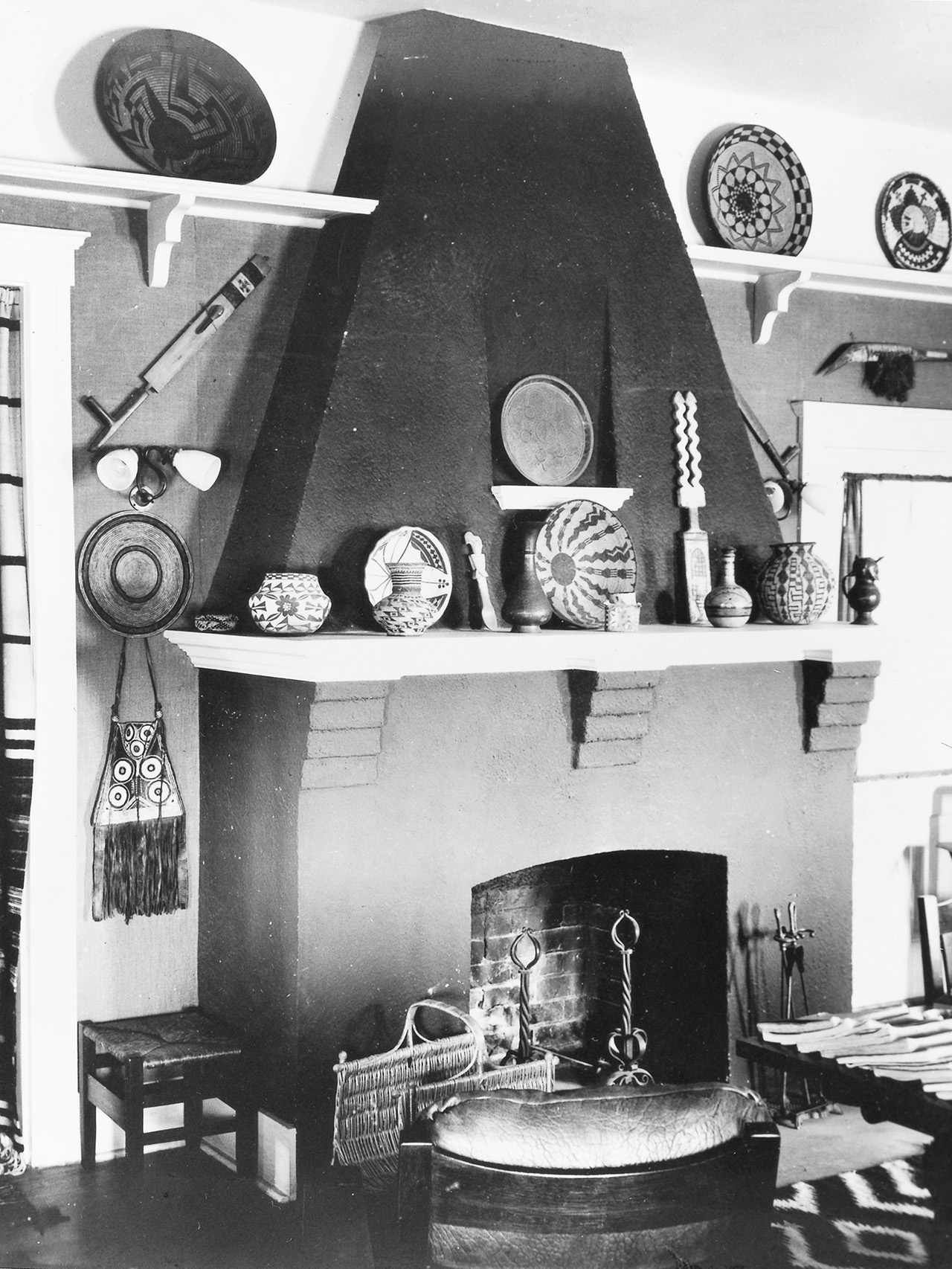 A black and white photo of a living room with a fireplace.