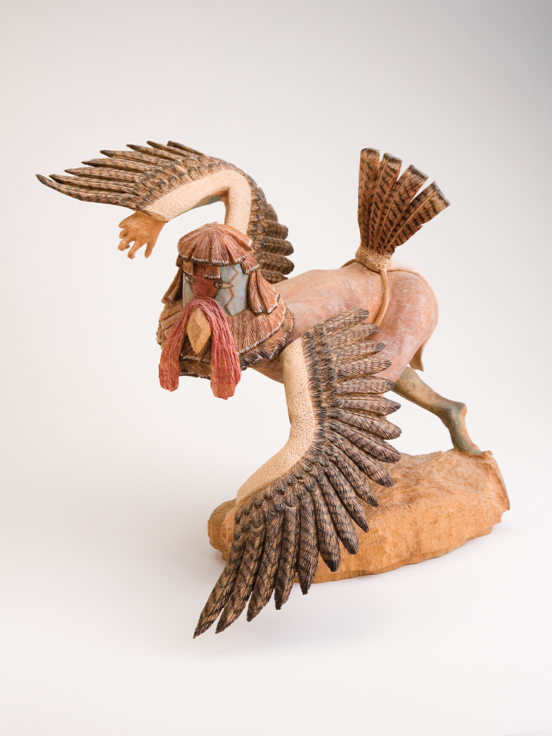 A wooden sculpture of a turkey figure with wings.