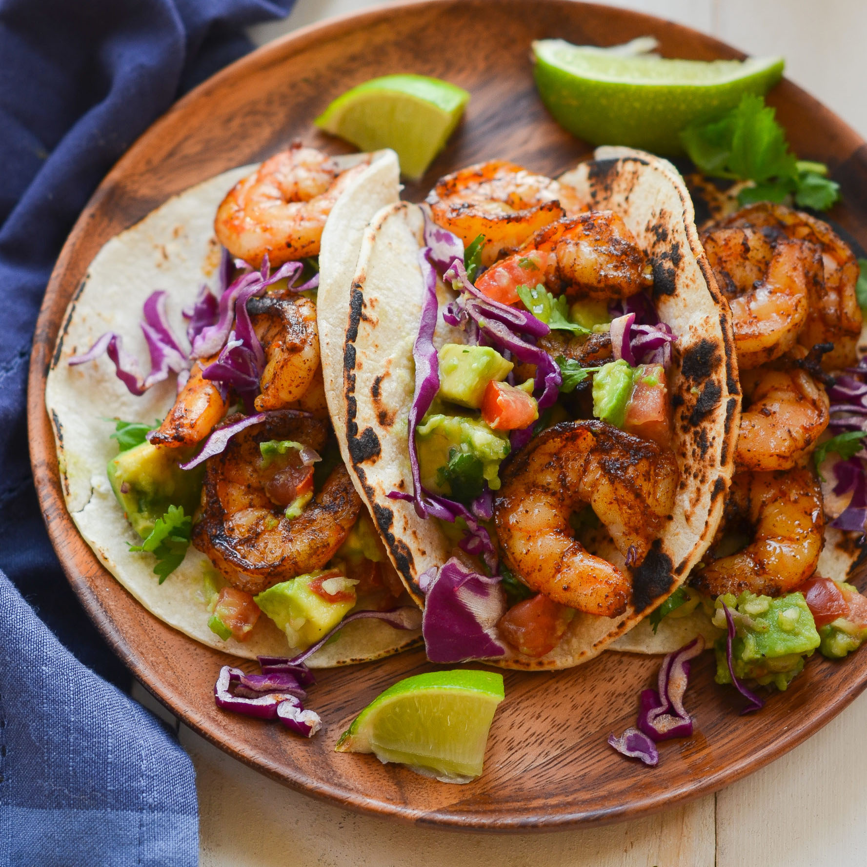 Grilled shrimp tacos on a wooden plate.