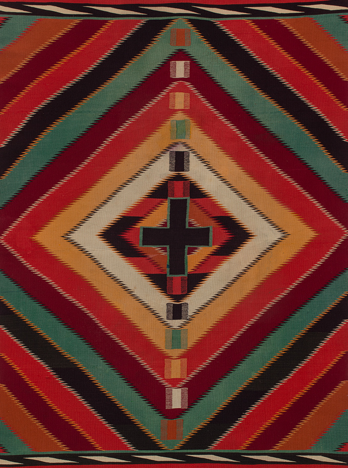 A colorful Navajo rug with a cross in the middle.