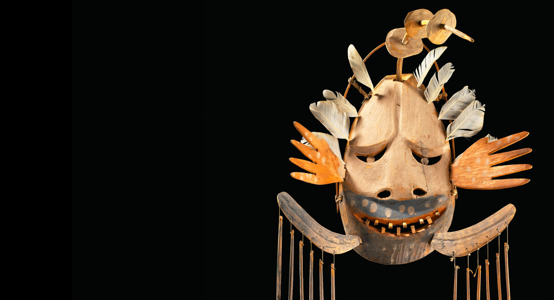 A wooden mask with rods hanging from it.
