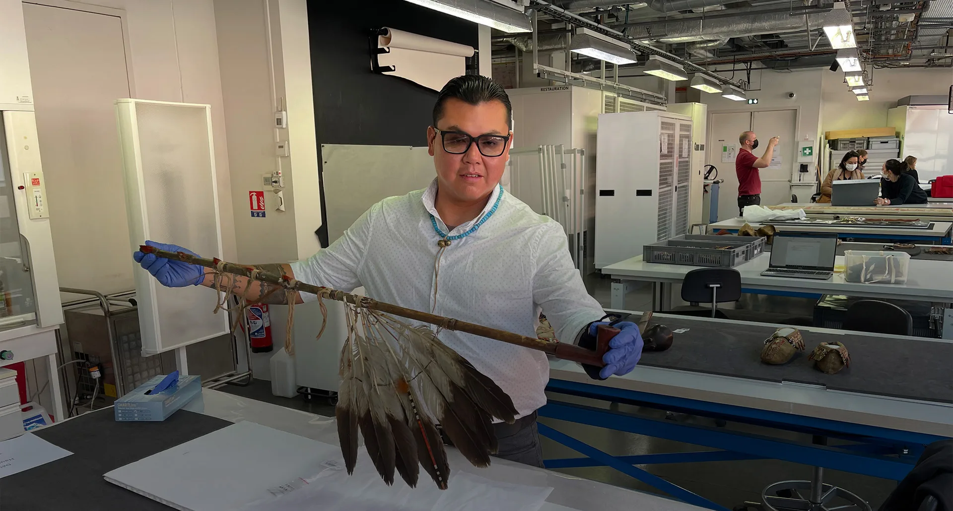 A person holding an object with feathers on it in front of a table.