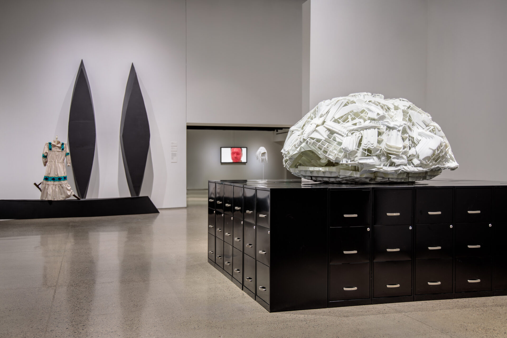A gallery with a large white sculpture on top of a black table.