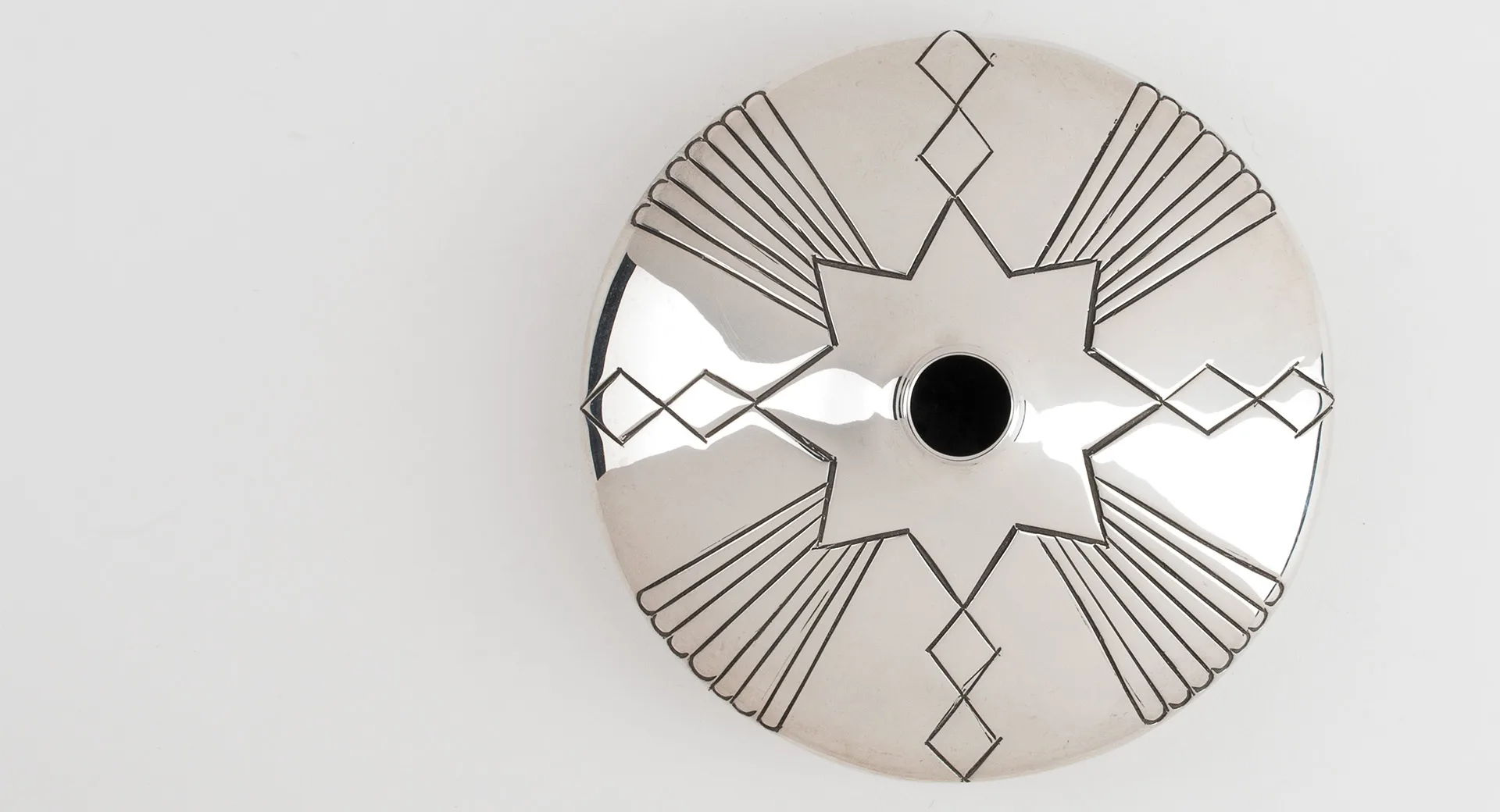 A silver seed pot with a star design on it.