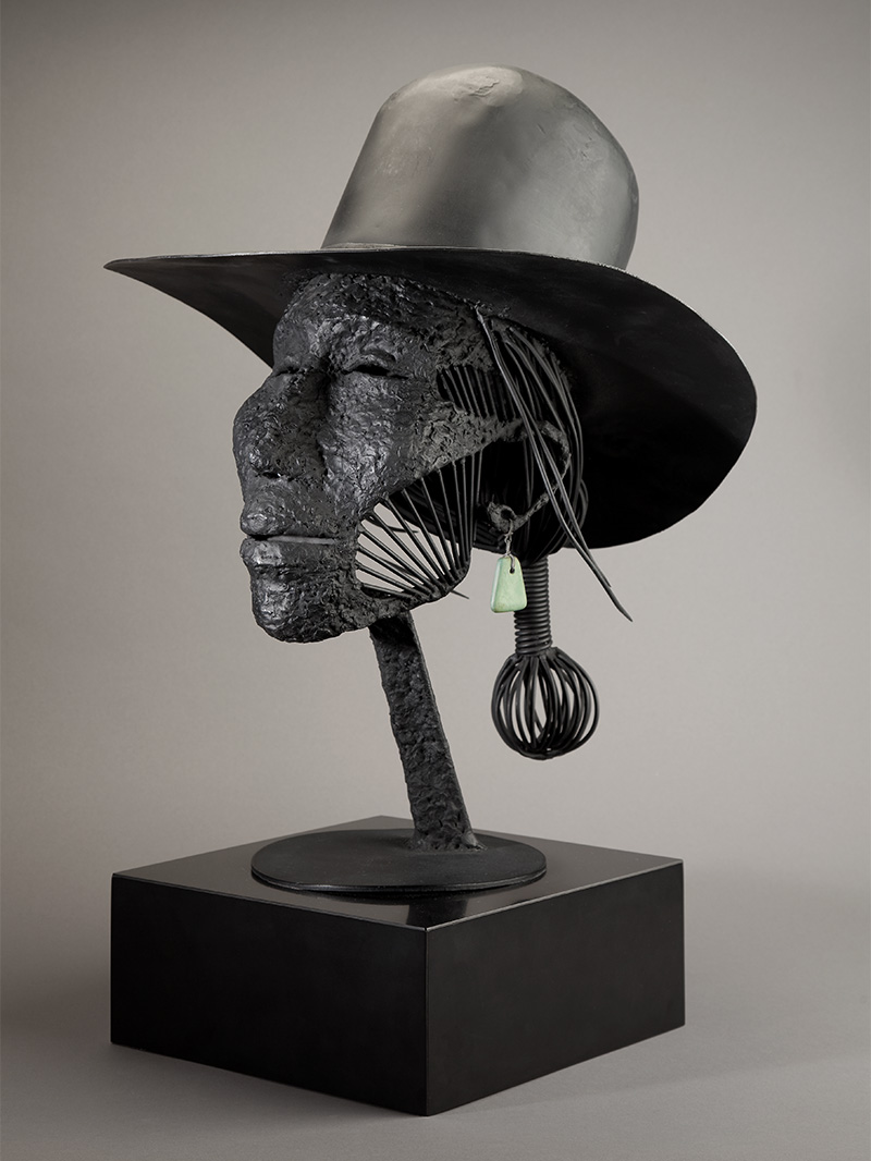 A sculpture of an Apache person's head wearing a hat.