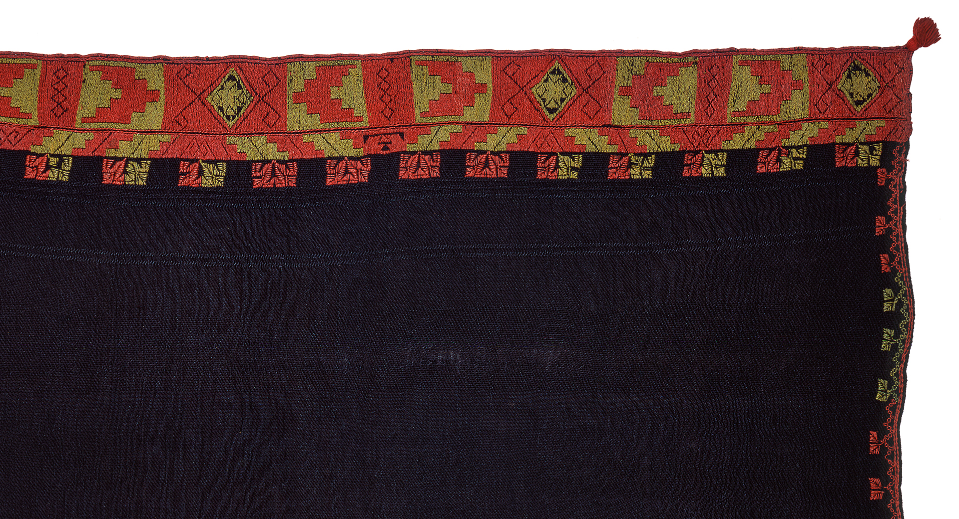 Detail of a black textile with a geometric orange and yellow design around the edge.