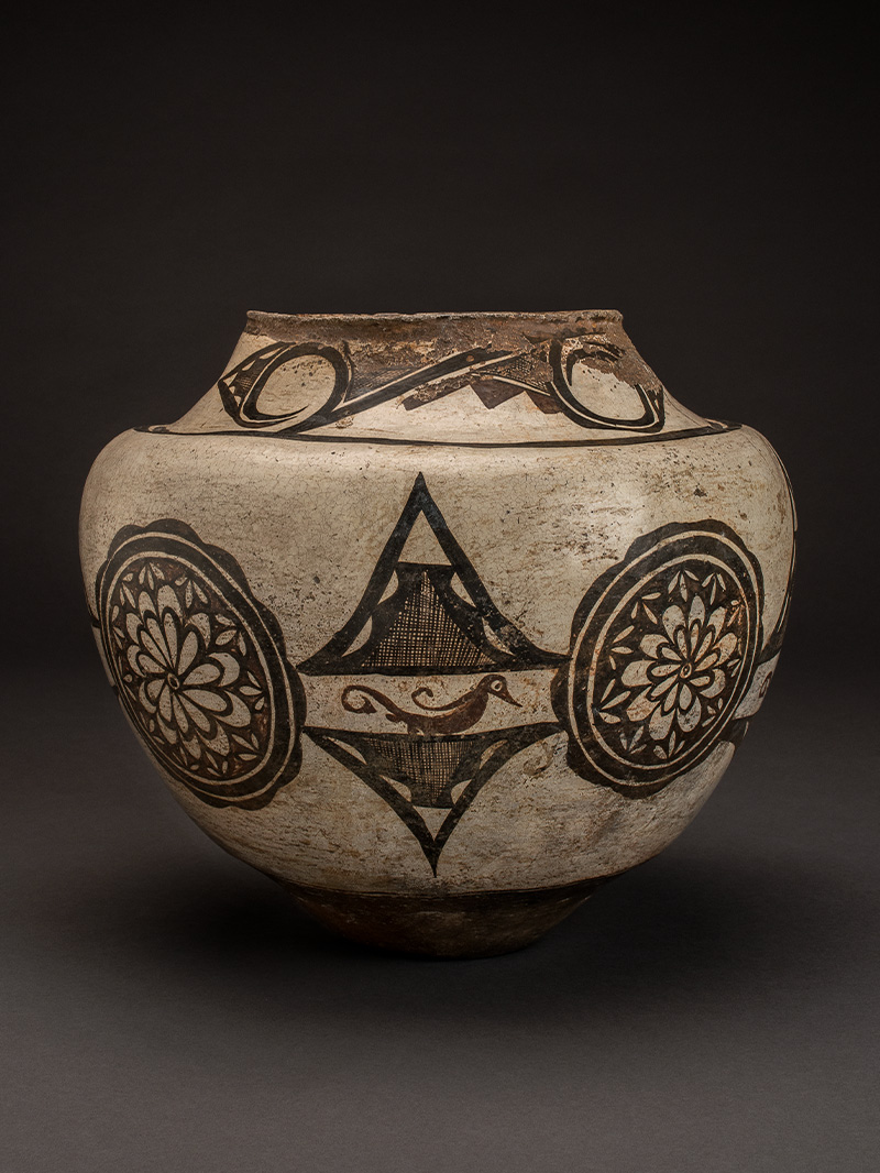 A white and black jar with designs on it.