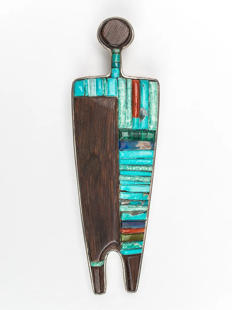 A wooden and turquoise pendant shaped like a figure.