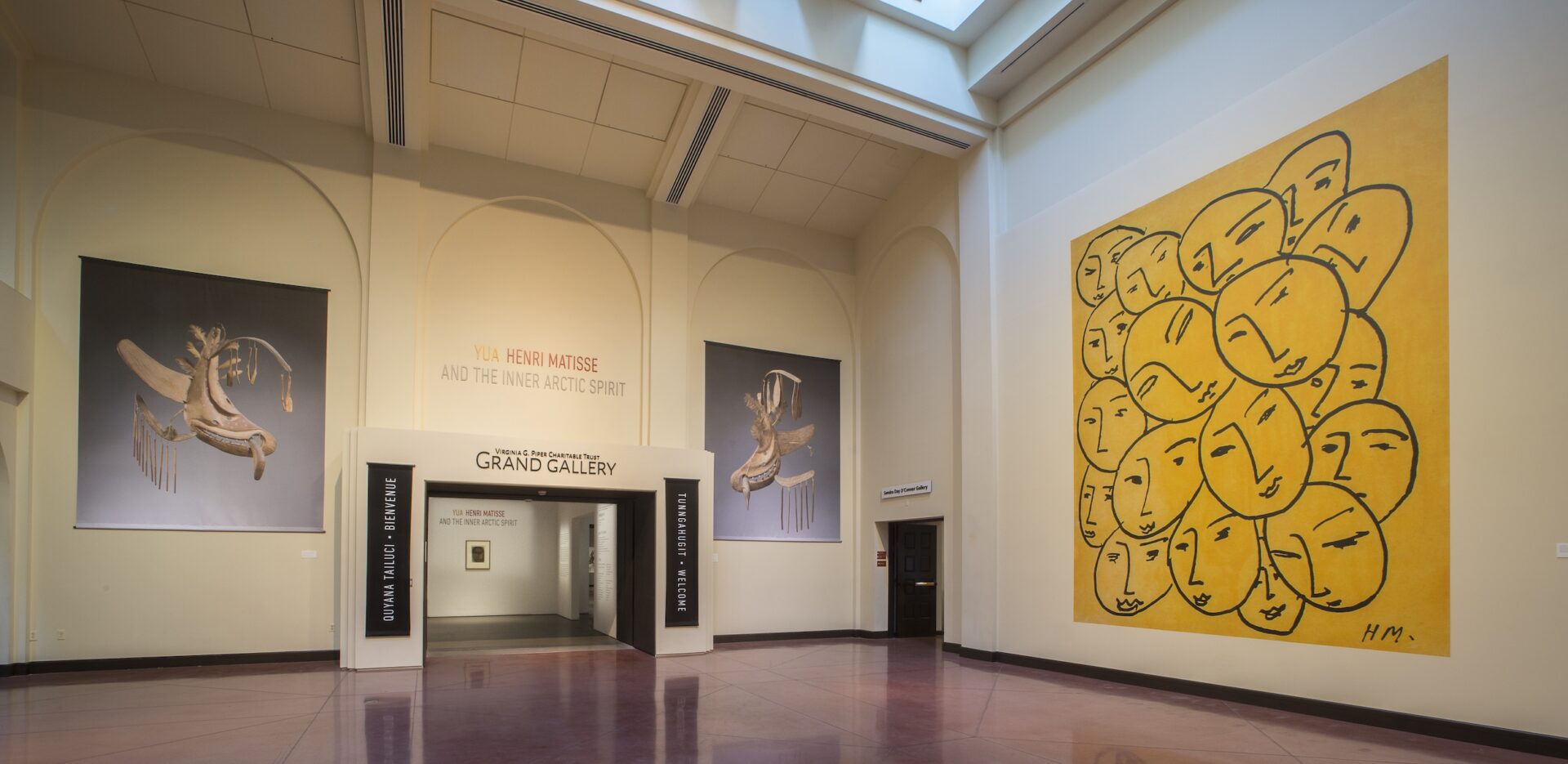 A museum gallery entrance hall with a big yellow painting and two paintings on the adjacent.