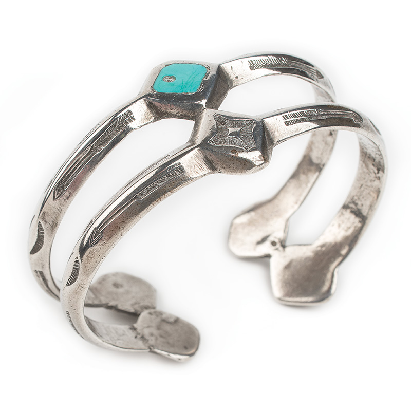 A silver cuff bracelet with a turquoise stone.