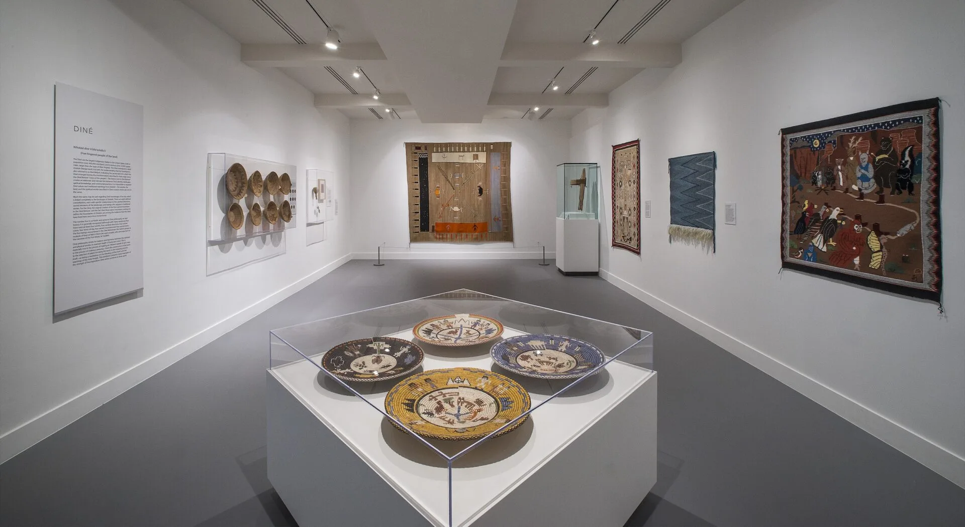 A room with a display of baskets, textiles on the walls and other items.
