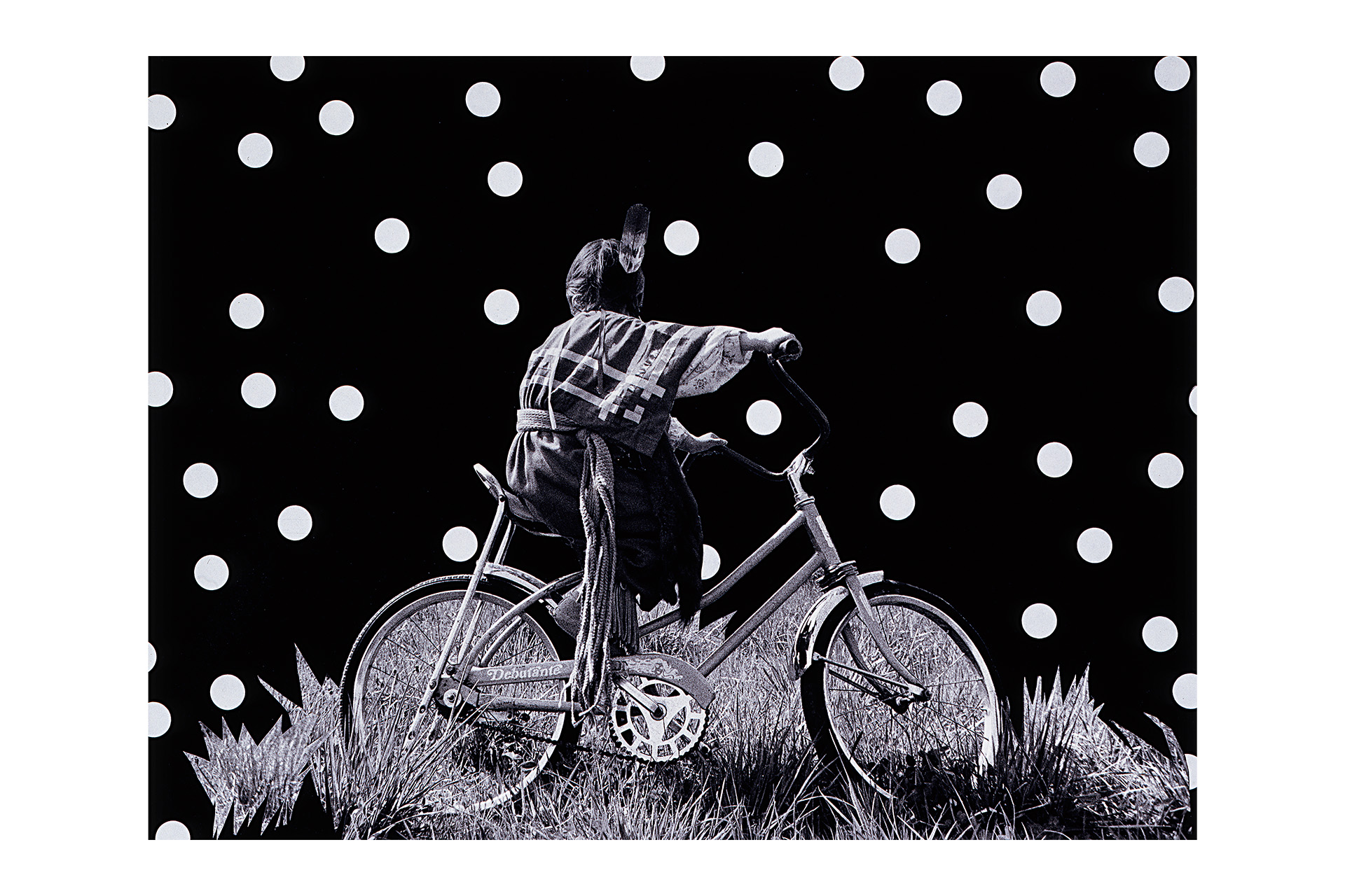 A black and white image of a person riding a bicycle with a black background that has while polka dots.