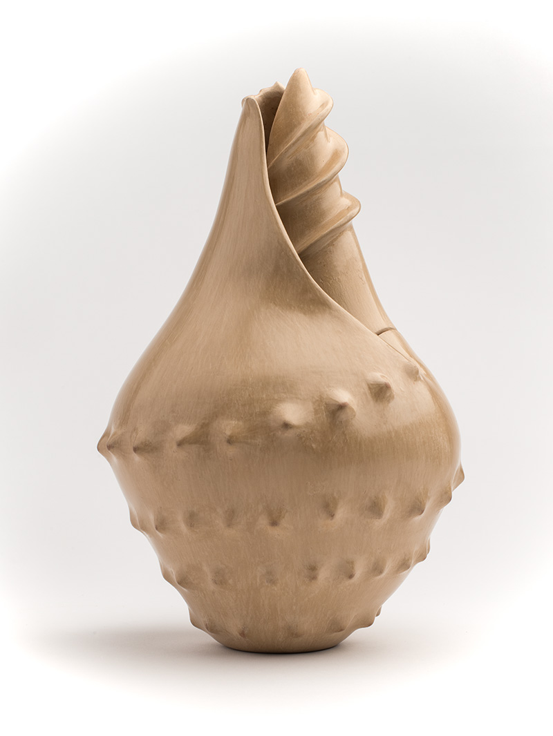 A tan pottery form reminiscent of a conch shell.