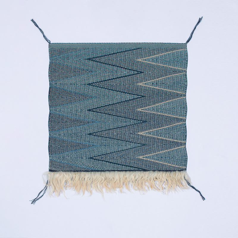 A blue and white woven textile with fringes.