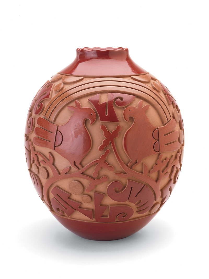 A red jar with sculpted birds and designs on it.