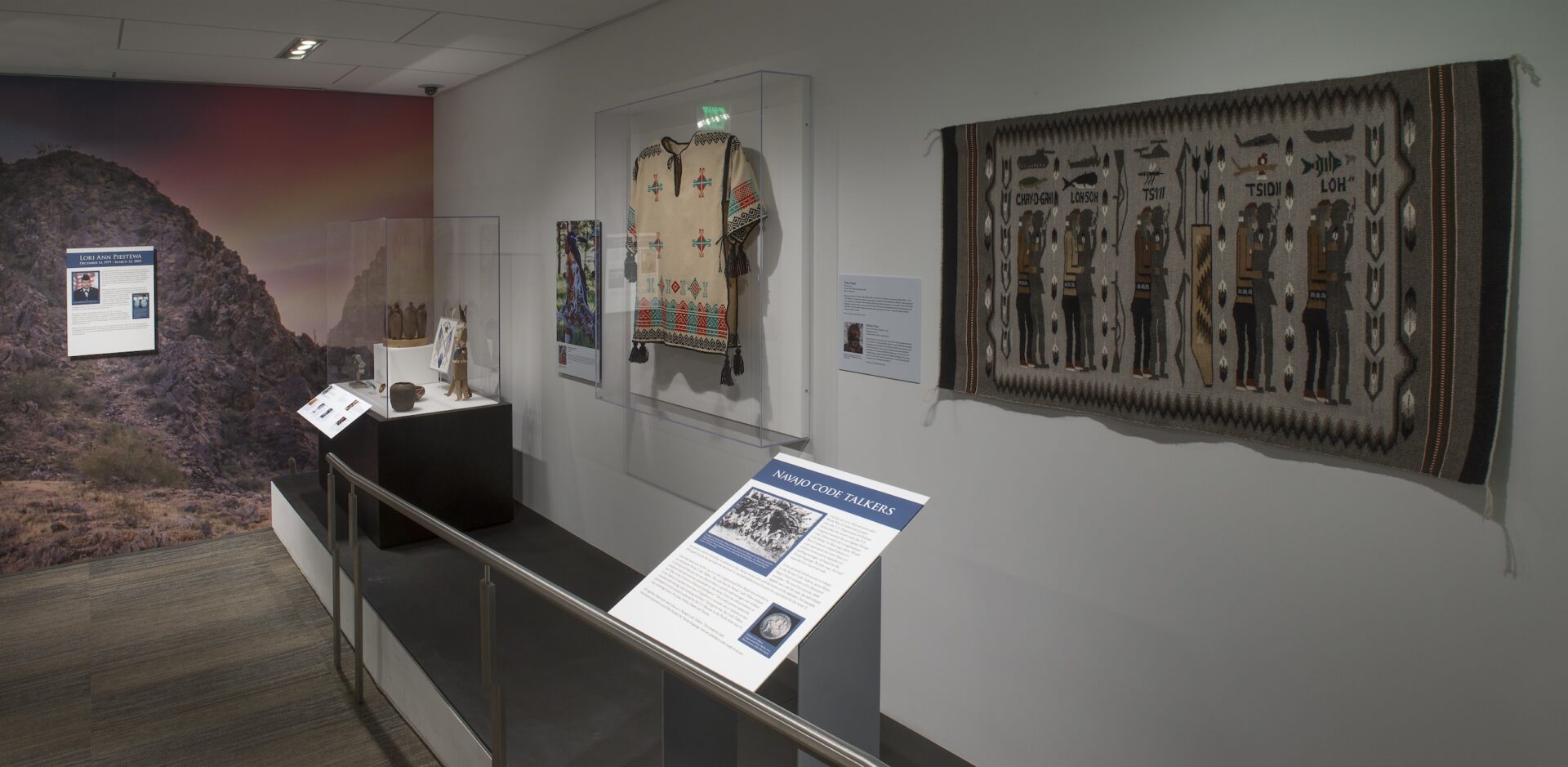 A display of Native fashion garments and textiles in a gallery.