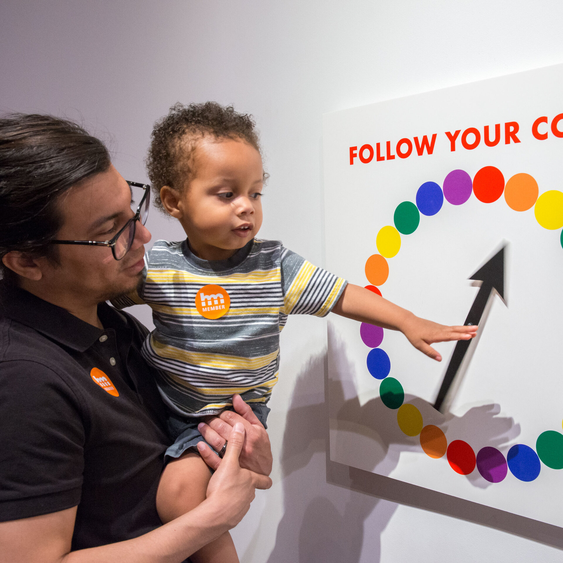 A man and a child looking at a sign that says follow your color.
