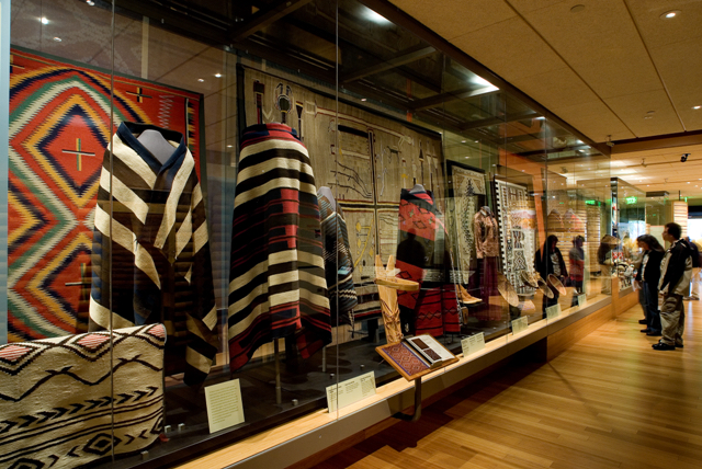 A display of Native garments and textiles in a museum gallery.