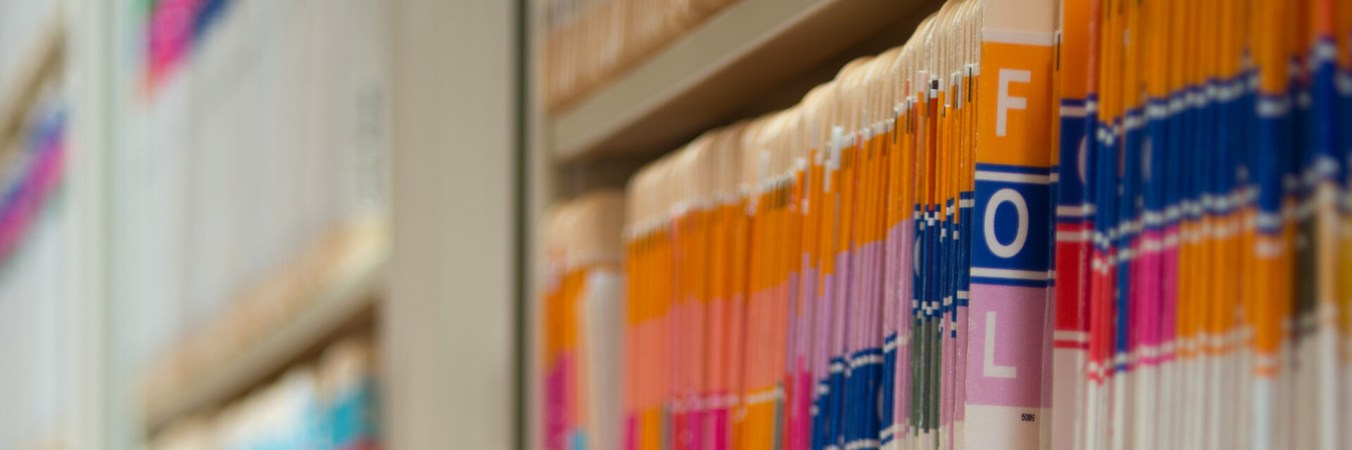 A row of colorful file folders on a shelf.
