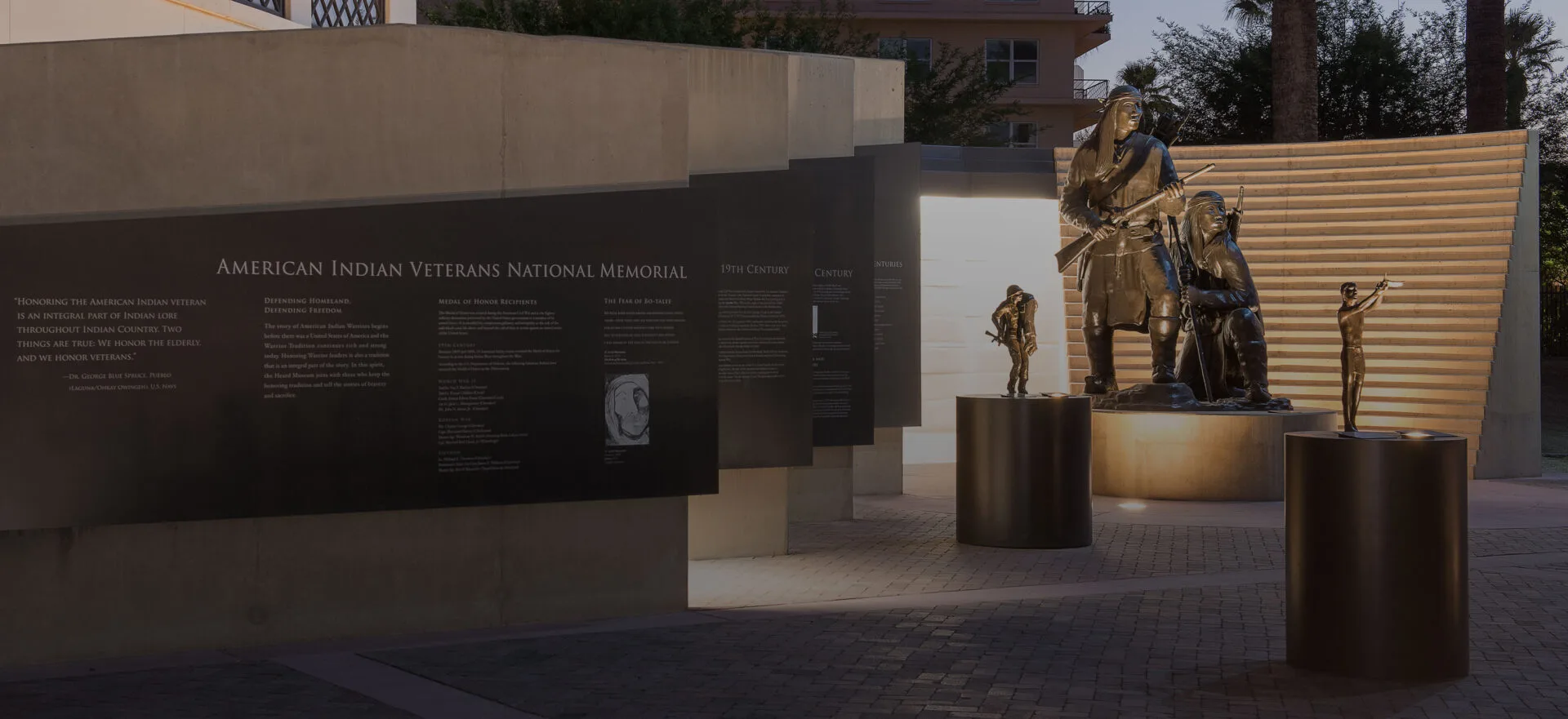 A sculpture of the American Indians Veterans National Memorial at dusk.