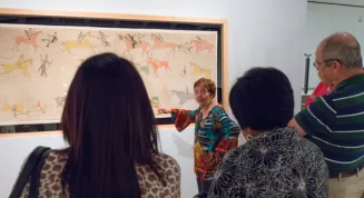 A group of people looking at a painting on display.