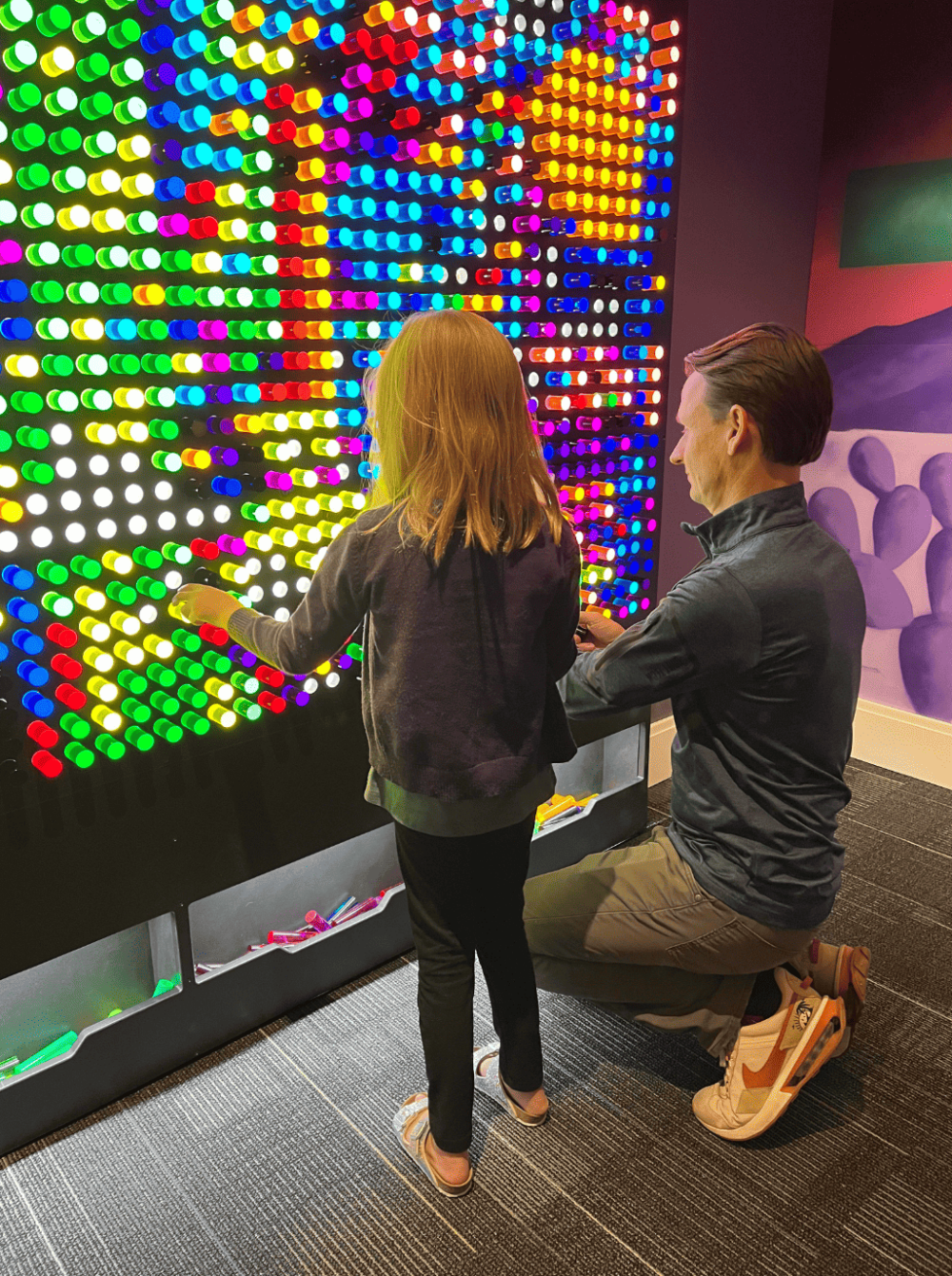 A man and a child looking at a colorful wall.