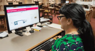 A woman using a computer in a library.