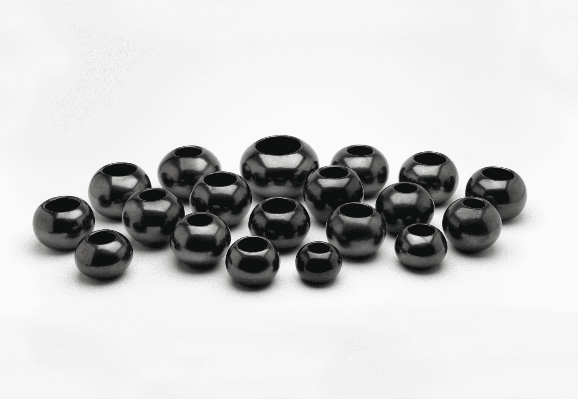A group of black beads arranged on a white surface.