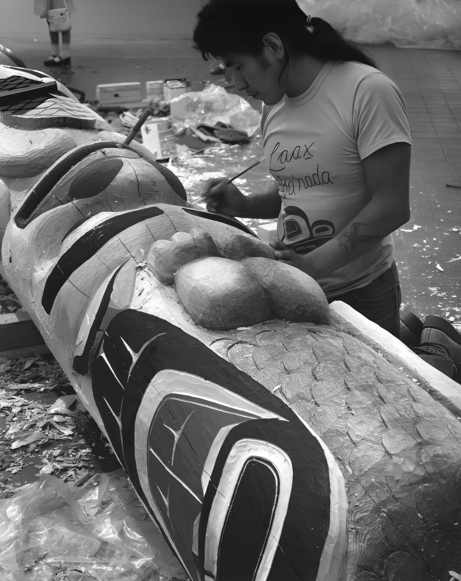 A man painting a totem pole.