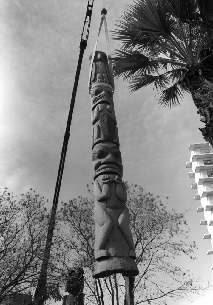 A totem pole with a palm tree and a street light.