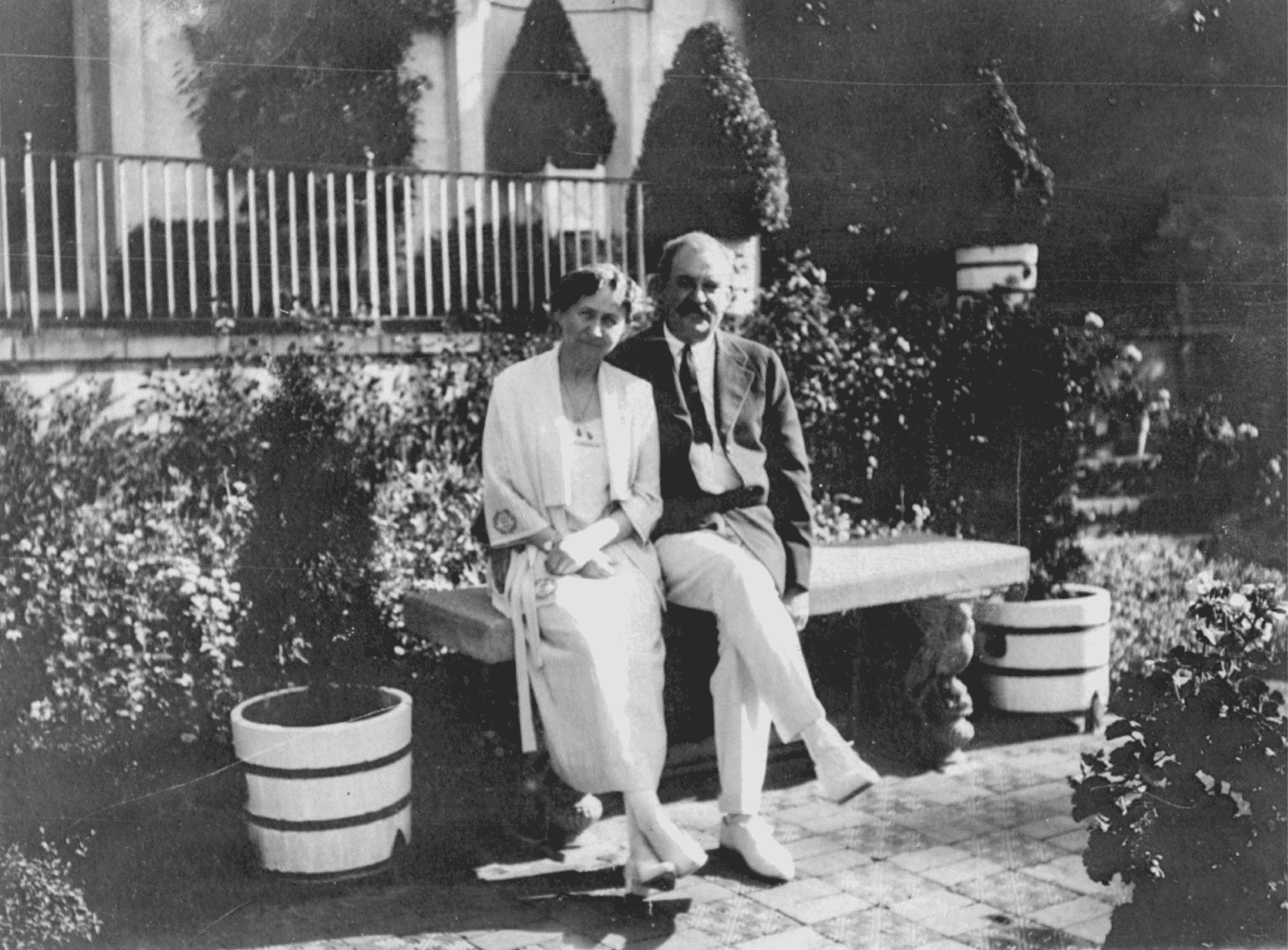 An old photo of a man and woman sitting on a bench.
