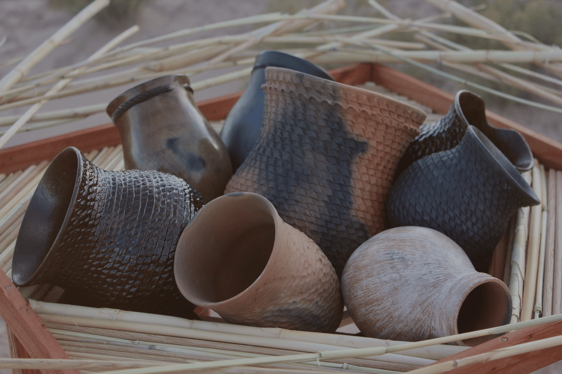 Clay pots in a basket on the ground.